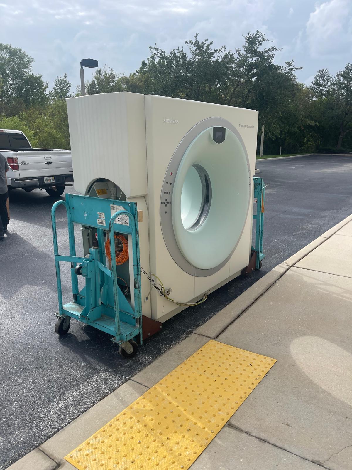 Siemens CT gantry secured on transport dollies outside a facility.